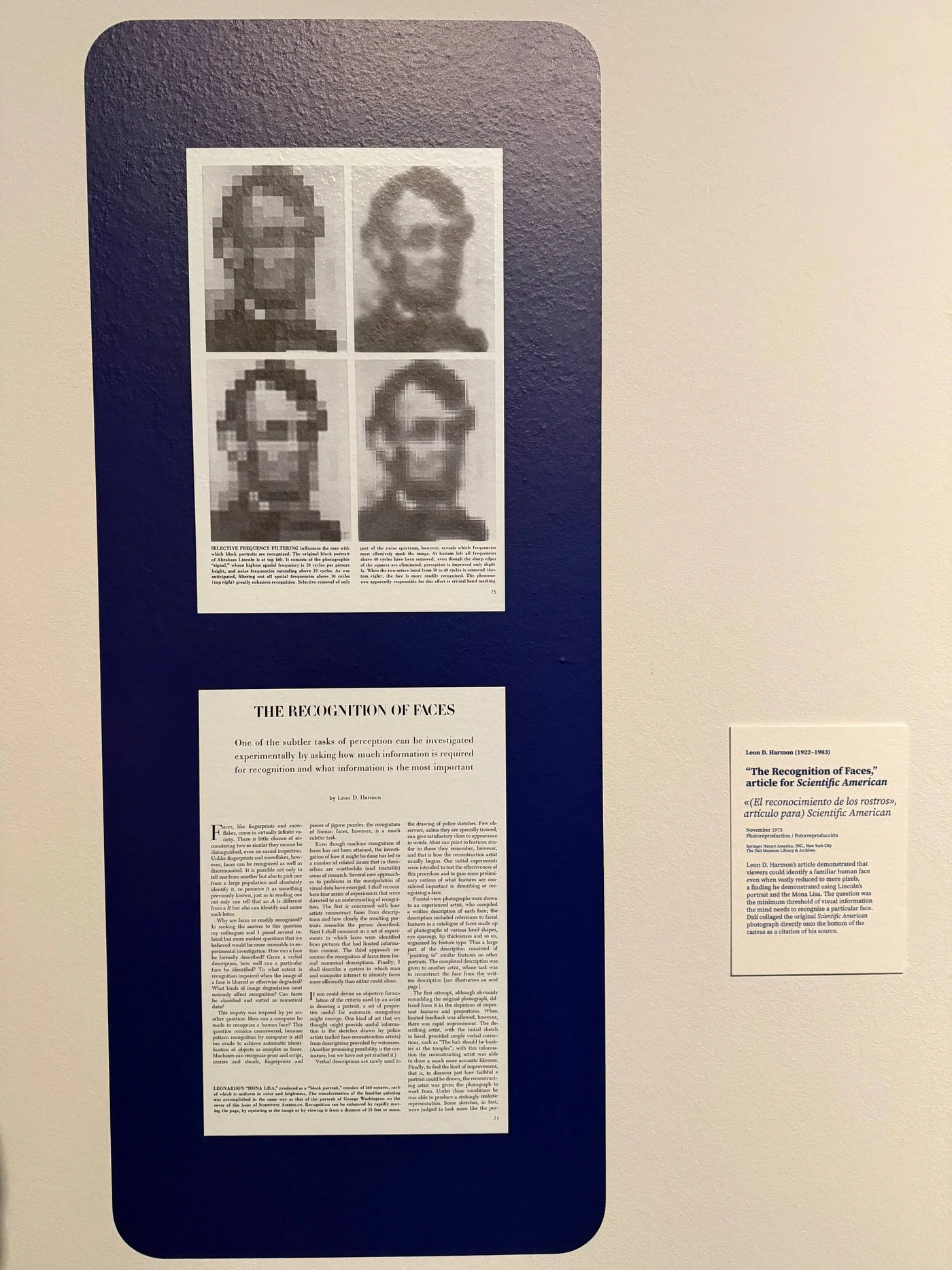 A deep blue panel at the Dalí Museum holding two framed pages from a 1973 Scientific American article. The upper page shows four coarse block portraits of Abraham Lincoln at different levels of filtering. The lower page is the article's opening page. A museum label sits to the right.
